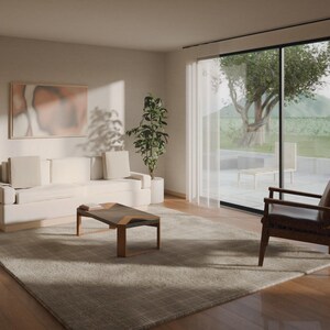 Puede incluir: Una sala de estar con un sof&aacute; de color crema con dos cojines a juego, una mesa de centro de madera, un sill&oacute;n de cuero marr&oacute;n oscuro, una l&aacute;mpara de pie, una planta en maceta y una alfombra grande sobre suelo de madera.