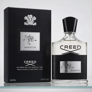 May include: A Creed Aventus fragrance bottle and its black box. The bottle is clear glass with a black label featuring a silver emblem of a rider on a horse and the text Aventus. The box displays the same emblem, text, and 100 ml 3.3 fl. oz.