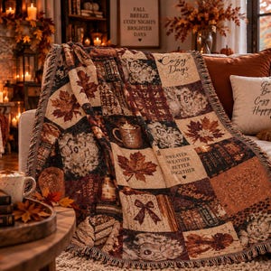 Peut inclure: Un plaid tissé présentant un motif patchwork d'illustrations sur le thème de l'automne, incluant des feuilles d'érable, une tasse de chocolat chaud, un nœud et le texte Cozy Days et Sweater Weather Better Together, avec des bords à franges.