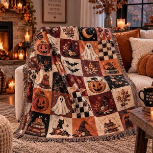 Op de afbeelding: Een geweven plaid met een patchworkontwerp met Halloween-thema-illustraties, waaronder pompoenen, geesten, zwarte katten, heksenhoeden, vleermuizen en maansikkels in tinten oranje, zwart, crème en bruin met een franjerand.