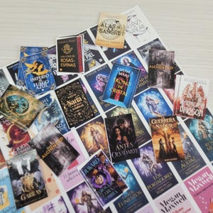 Puede incluir: Una colección de portadas de libros en miniatura con varios títulos y autores, incluyendo Alianzas de Sangre, Alas de Sangre, Trono de Cristal y otros. Las pequeñas impresiones rectangulares muestran diversas ilustraciones gráficas y texto en español.