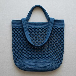 May include: A deep blue crochet tote bag featuring a wide, open-work diamond mesh pattern throughout the main body, a solid reinforced base, and two integrated shoulder straps constructed with a dense, tight stitch for added durability.