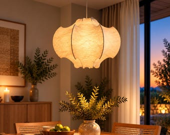 May include: A pendant light fitting with a textured, off-white, multi-lobed shade suspended from a thin cord. The lamp emits a warm, diffused glow, featuring a rounded, organic shape with vertical seams that create a soft, pleated appearance.