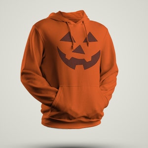 Może przedstawiać: Pomarańczowa bluza z kapturem z czarno-białym nadrukiem twarzy jack-o'-lantern na przodzie.