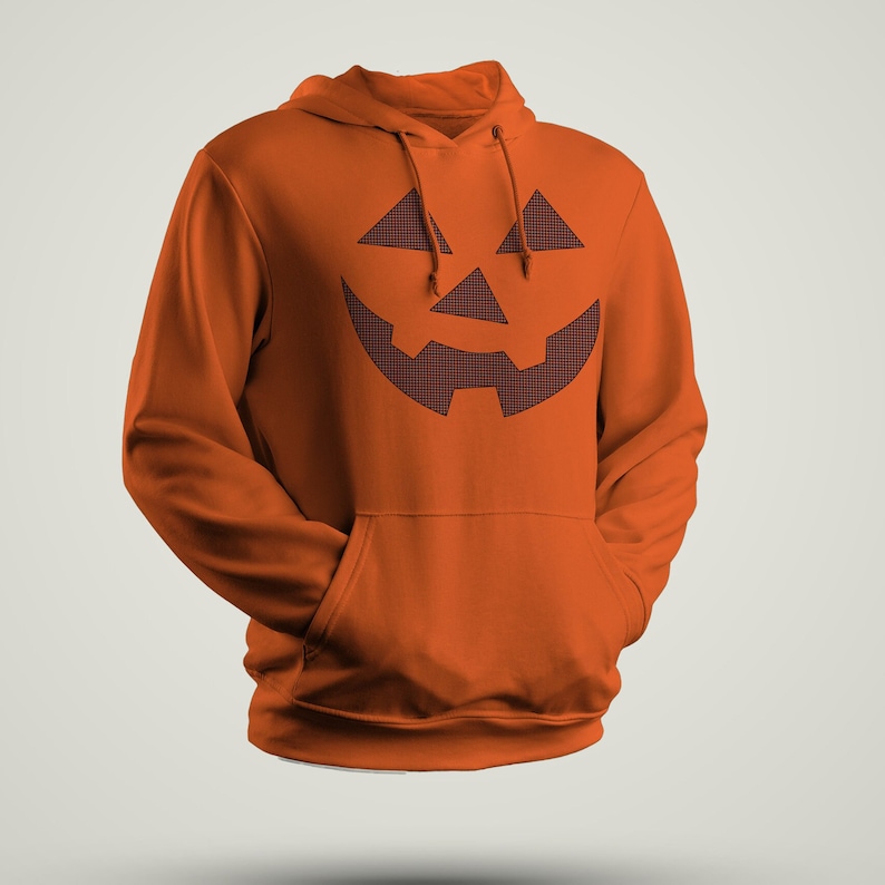 Może przedstawiać: Pomarańczowa bluza z kapturem z czarno-białym nadrukiem twarzy jack-o'-lantern na przodzie.