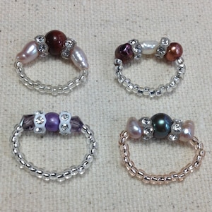 Puede incluir: Cuatro anillos de cuentas con perlas y pedrería de diferentes colores. Los anillos están hechos con cuentas de color plateado y dorado.