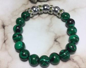 May include: A green and black malachite beaded bracelet with silver and green gemstone accents.