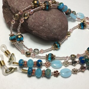 May include: A multi-strand beaded eyeglass chain with blue, turquoise, and copper beads. The chain has gold-toned metal clasps for attaching to eyeglasses.