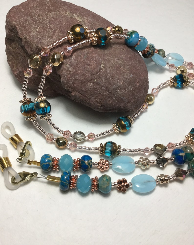 May include: A multi-strand beaded eyeglass chain with blue, turquoise, and copper beads. The chain has gold-toned metal clasps for attaching to eyeglasses.
