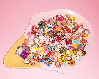 Puede incluir: Un plato de cerámica en forma de cono de helado rosa y amarillo lleno de pegatinas de personajes de dibujos animados de colores. Las pegatinas son principalmente rosas, amarillas, azules y verdes.