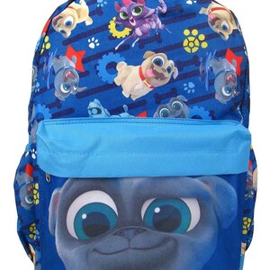 Può includere: Zaino blu con un volto di cane dei cartoni animati sulla tasca anteriore. Il corpo principale presenta un motivo ripetuto di cuccioli dei cartoni animati, ossa e ingranaggi su sfondo blu. Ha una tasca anteriore e spallacci blu.