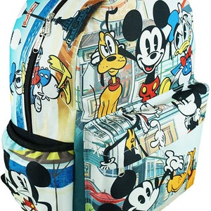 May include: A white canvas backpack with a colorful print of Mickey Mouse, Donald Duck, and Goofy. The print features a cityscape background with various buildings and street signs. The backpack has a large main compartment, a front pocket, and adjustable straps.