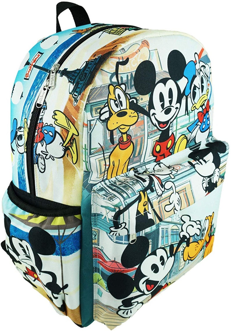 May include: A white canvas backpack with a colorful print of Mickey Mouse, Donald Duck, and Goofy. The print features a cityscape background with various buildings and street signs. The backpack has a large main compartment, a front pocket, and adjustable straps.