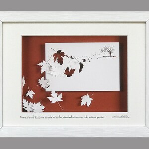 Pode incluir: Uma moldura branca com um passe-partout castanho e um recorte de papel branco de uma árvore com folhas a serem levadas pelo vento. O texto "Comme le vent d'automne emporte les feuilles, s'enuclent ens souvenirs des saisons passées." está escrito abaixo do recorte. A assinatura do artista "MAR" está no canto inferior direito.