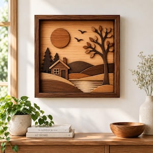 May include: A square wooden wall art piece featuring a layered landscape scene with a cabin, pine trees, a large sun, a deciduous tree, and rolling hills. The artwork is constructed from various shades of natural wood, creating a dimensional effect.