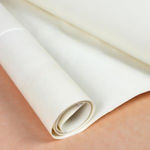 May include: A roll of smooth, opaque white material with a matte finish. The material is partially unrolled, revealing a cylindrical core and a flat, extended section. The surface appears uniform and clean, showing no visible patterns or textures.