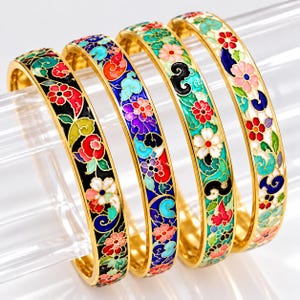 May include: Four gold-tone metal bangle bracelets featuring intricate cloisonné enamel work. Each bracelet displays a vibrant floral and swirling cloud pattern in various colours including red, blue, green, pink, and black, set against different base colours.