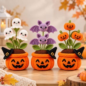 May include: Three crocheted Halloween-themed potted plants. Each orange pot features a jack-o'-lantern face and a black witch hat. The first pot holds three white ghosts, the second holds two purple bats, and the third holds three orange pumpkins.