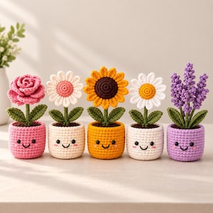 May include: Five crocheted potted plants featuring a pink rose, a white daisy with a pink center, a yellow sunflower, a white daisy with a yellow center, and purple lavender. Each plant sits in a small, round, crocheted pot with a smiling face.