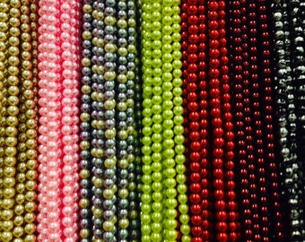 May include: Assortment of pearl strands in various colors, including gold, pink, gray, green, red, black, and dark red.