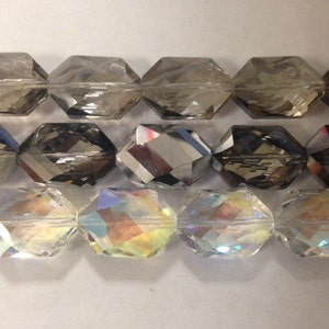 Peut inclure: Trois rang&eacute;es de perles de verre facett&eacute;es. La rang&eacute;e du haut est gris fonc&eacute;, la rang&eacute;e du milieu est gris clair et la rang&eacute;e du bas est transparente avec des couleurs arc-en-ciel iris&eacute;es.