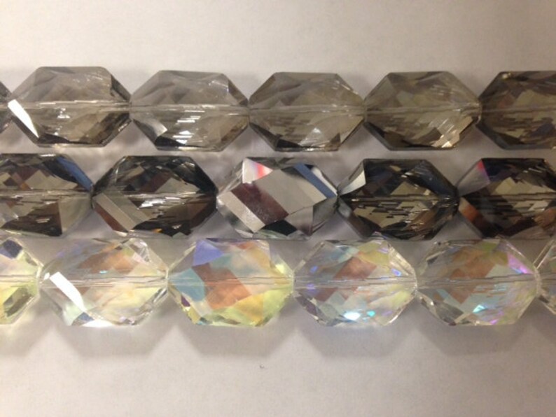 Peut inclure: Trois rang&eacute;es de perles de verre facett&eacute;es. La rang&eacute;e du haut est gris fonc&eacute;, la rang&eacute;e du milieu est gris clair et la rang&eacute;e du bas est transparente avec des couleurs arc-en-ciel iris&eacute;es.