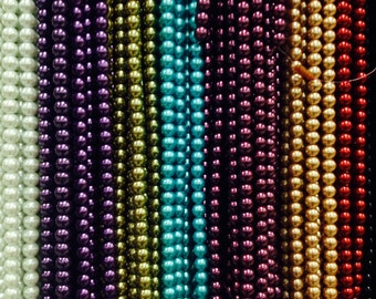 May include: Rows of colorful beads in various shades, including white, purple, teal, gold, and red. The beads are strung together, creating a textured and visually appealing display. The beads are small and round, and the colors are vibrant.