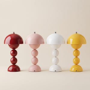 May include: Four table lamps arranged in a row, each featuring a glossy finish and a spherical base design. The lamps are colored deep red, soft pink, bright white, and vibrant yellow. Each lamp has a dome-shaped shade and a small silver finial.