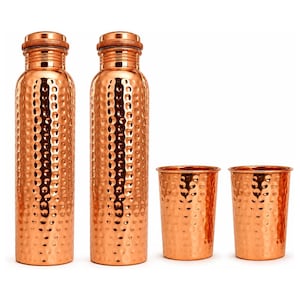 May include: Two tall, cylindrical copper water bottles with a hammered texture and matching screw-top lids, accompanied by two matching hammered copper tumblers. Each item features a polished, reflective metallic finish in a warm copper tone.