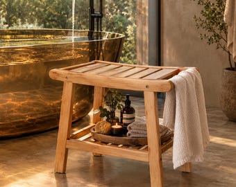 May include: A rectangular wooden shower bench with a slatted top and a lower shelf. A white textured towel hangs over the side. The lower shelf holds a wooden tray with a small brown bottle, a sponge, a candle, and folded towels. WoodCarvedStories.