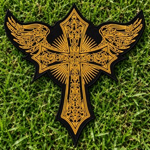 Puede incluir: Un parche bordado negro que presenta una cruz central con intrincados detalles en hilo dorado y alas estilizadas que se extienden desde los lados. El diseño incluye líneas radiantes de rayos de sol y patrones de volutas ornamentales.