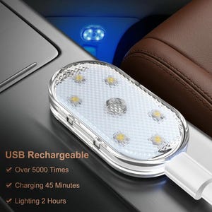 May include: An oval-shaped LED interior car light with a textured white cover and six small light diodes. The device is USB rechargeable and features text stating USB Rechargeable, Over 5000 Times, Charging 45 Minutes, and Lighting 2 Hours.