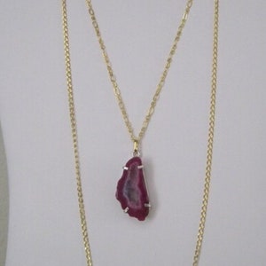 May include: A gold chain necklace with a pink agate pendant. The pendant is a slice of agate with a natural crystal formation.