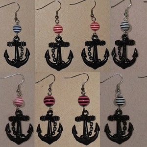 May include: A set of six pairs of black anchor earrings with striped beads. The beads are in three colors: black and white, pink and white, and red and white.