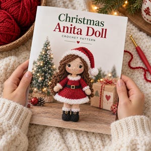 Könnte beinhalten: Eine gedruckte Broschüre mit dem Titel Christmas Anita Doll Crochet Pattern, die eine gehäkelte Puppe mit langem braunem Haar in einem rot-weißen Weihnachtsmann-Outfit, passender Mütze und schwarzen Stiefeln vor einem festlichen Hintergrund zeigt.