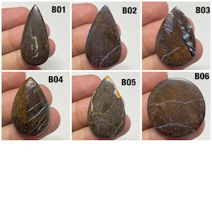 以下が含まれることがあります： B01からB06のラベルが付いた6つの研磨されたボルダーオパール。これらの石は、濃い茶色の鉄鉱石マトリックスを特徴とし、青、紫、金の虹色の脈があります。5つは涙の形で、1つは円形です。