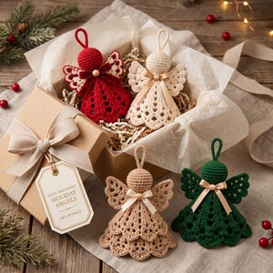 May include: Four hand-crocheted angel ornaments in red, cream, beige, and dark green, each with a satin ribbon bow and hanging loop. Two angels are inside a gift box with tissue paper, and a tag reads: HAND-CROCHETED HOLIDAY ANGELS GIFT OF PEACE.