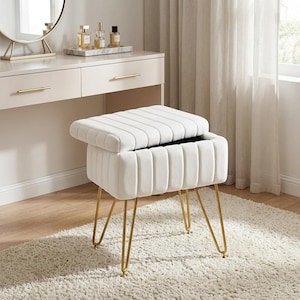 May include: A white rectangular storage ottoman featuring a tufted, vertically channeled velvet upholstery and a hinged lid. The piece is supported by four slender, gold-toned metal hairpin legs, providing a stable base for this functional furniture item.