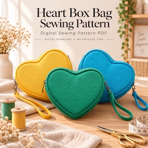 May include: Three heart-shaped bags in yellow, green, and blue, each with a wrist strap and zipper. The text reads Heart Box Bag Sewing Pattern, Digital Sewing Pattern PDF, Digital Download, No Physical Item. Sewing supplies are visible nearby.