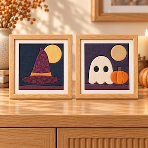 May include: Two square framed fabric art pieces featuring Halloween themes. The left frame shows a purple patterned witch hat against a dark blue background with a yellow moon. The right frame displays a white ghost and orange pumpkin.
