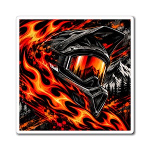 May include: A black motocross helmet with a visor and goggles featuring a reflective orange lens. The design includes a graphic of stylised orange and yellow flames surrounding the helmet, with a mountain and forest silhouette in the background.