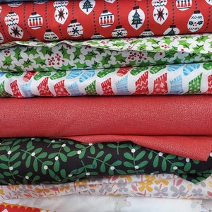 May include: A stack of six fabric scraps with various Christmas-themed patterns. The patterns include red with white ornaments, green with holly leaves, white with blue and red stockings, red with a speckled texture, black with green leaves, and white with yellow and pink flowers.