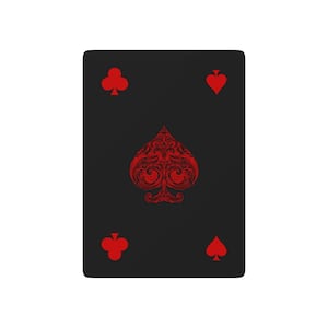 May include: A rectangular playing card with a solid black background. The center features a large, ornate red spade symbol with intricate filigree patterns. Smaller red club and heart symbols are positioned in the four corners of the card.