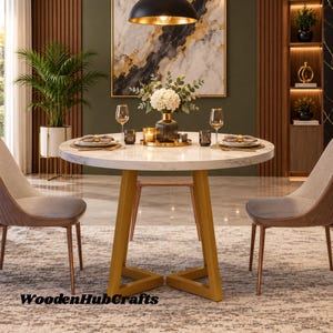 May include: A round white marble dining table with a gold metal base, featuring two grey upholstered chairs. The table is set with two wine glasses, two small dark glasses, a central glass vase with white flowers, and two candles on a gold tray.