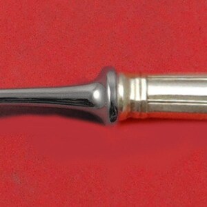 May include: A silver fork with a gold-plated handle. The handle has a simple, elegant design with a rounded end.