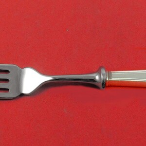 May include: A silver fork with a gold-plated handle. The handle has a geometric design.