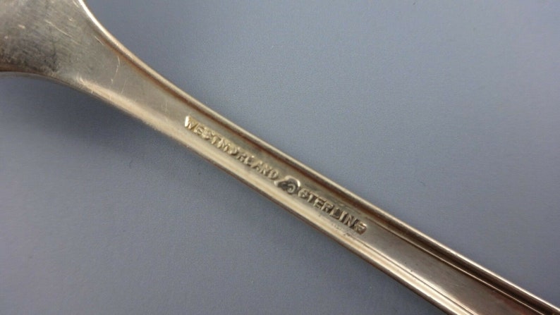 Puede incluir: Primer plano de la parte posterior de una cuchara de plata con la inscripci&oacute;n "Westmoreland Sterling" en el mango.