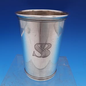May include: A silver cup with a beaded rim and the initials "SB" engraved on the side.