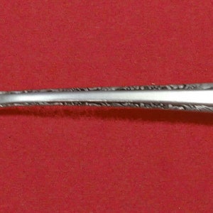 May include: A silver serving spoon with an ornate design and a small, oval-shaped opening in the bowl.