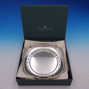 May include: A silver serving tray with a square shape and a raised rim. The tray is in a green box with the words "Unoargento" printed on the lid.